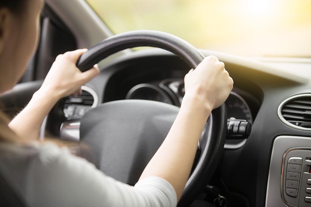 Close-up of female hands on the steering wheel